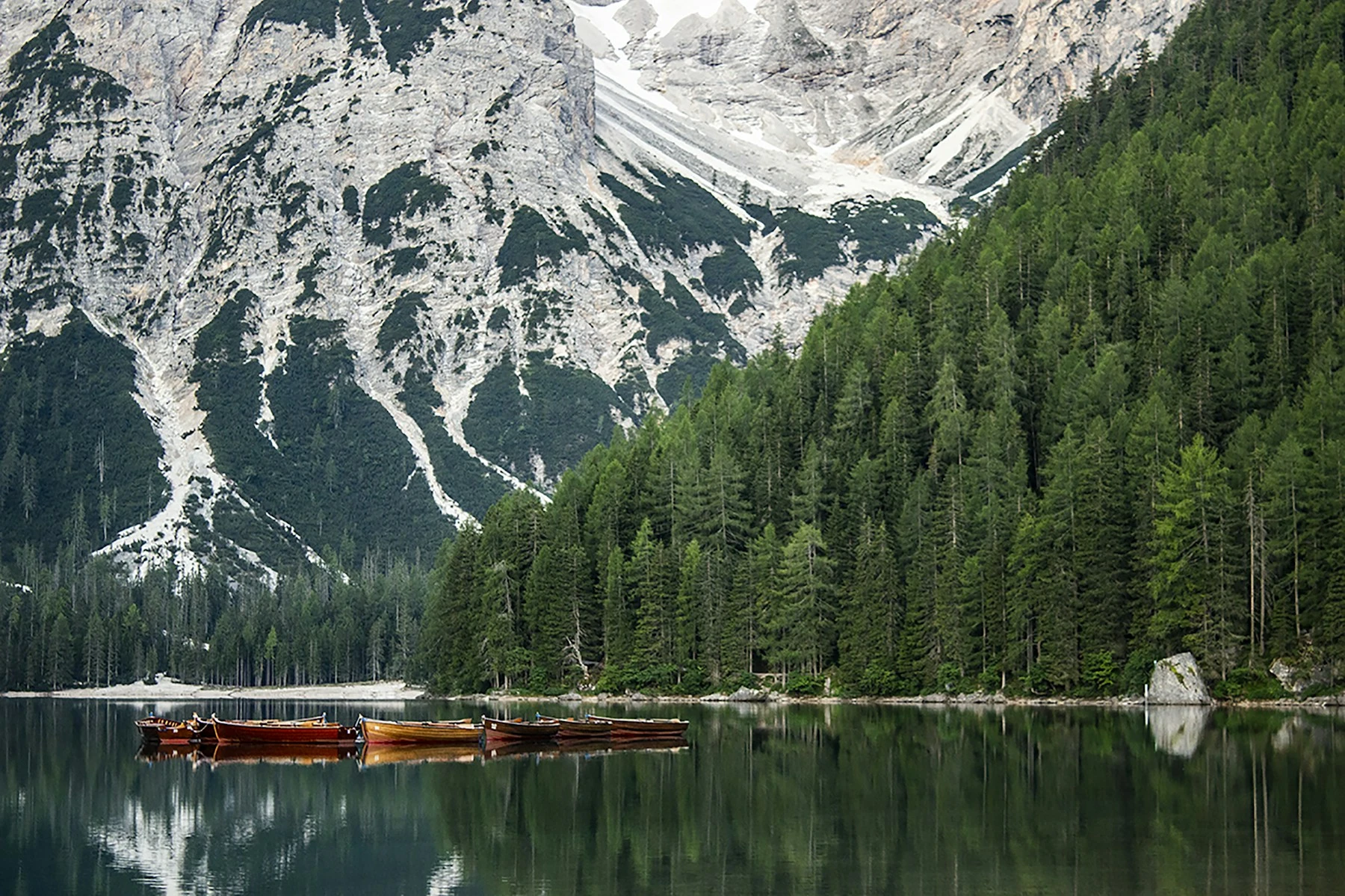 Wooden boats on a turquoise alpine lake beneath the Dolomites